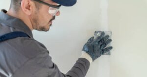 Commercial painter meticulously sanding a wall, crucial for preventing paint fading and ensuring a lasting finish.