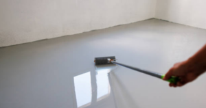 Professional applying new epoxy flooring, preventing future paint fading and wear in a commercial space.
