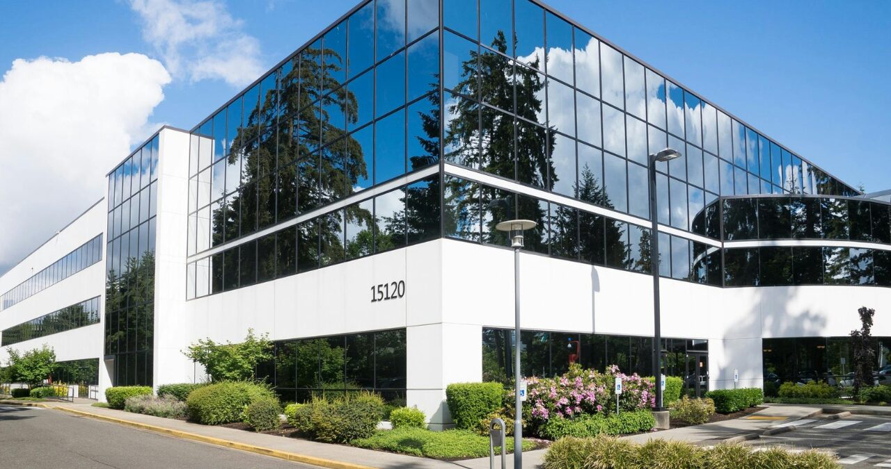 Exterior of a modern commercial office building with large windows and clean white paint, highlighting the value of painting your office.