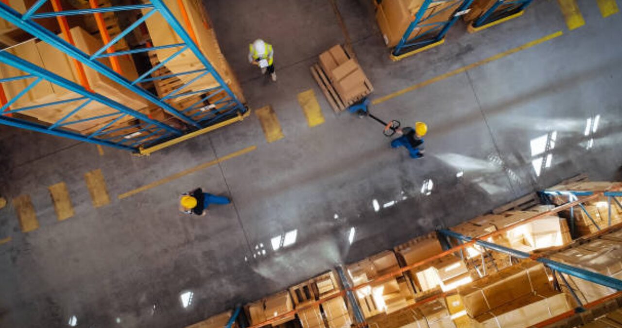 An aerial view of a clean, well-lit warehouse with clear safety lines, demonstrating the benefits of a professional Warehouse Paint Renewal.