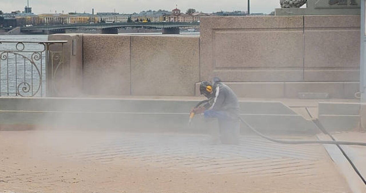 A professional performing Sandblasting and Ecoblasting on a stone surface to remove old layers and prepare for a new coating.