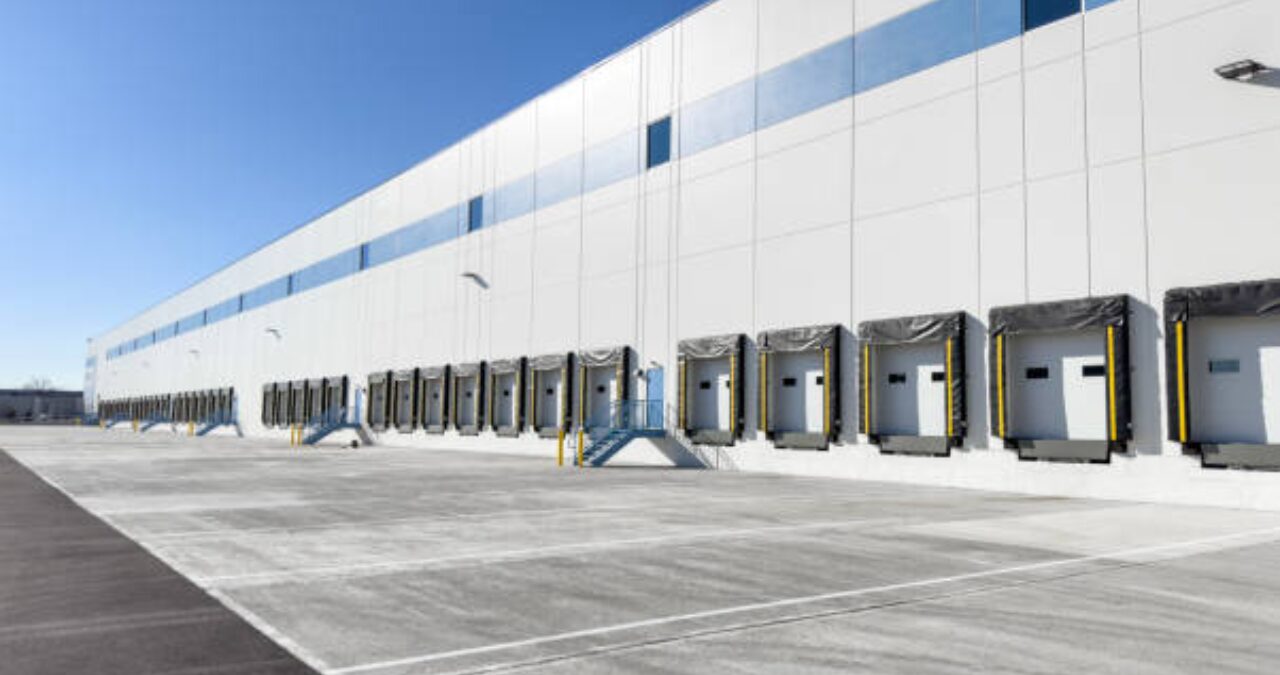 Fresh, professional Commercial Exterior Painting on a large distribution center with multiple loading docks and a clean parking area.