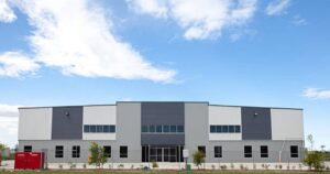 Modern industrial building with gray and white panels, showcasing a multi-color Commercial Exterior Painting scheme for a clean, contemporary look.