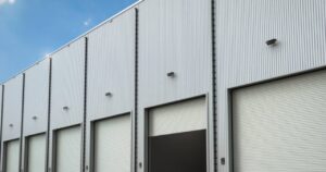 Close-up of industrial roll-up doors and corrugated metal siding needing professional Commercial Exterior Painting and maintenance.