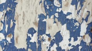 Severe peeling blue paint on a commercial wood surface in Knoxville TN, indicating the need for professional exterior repainting.