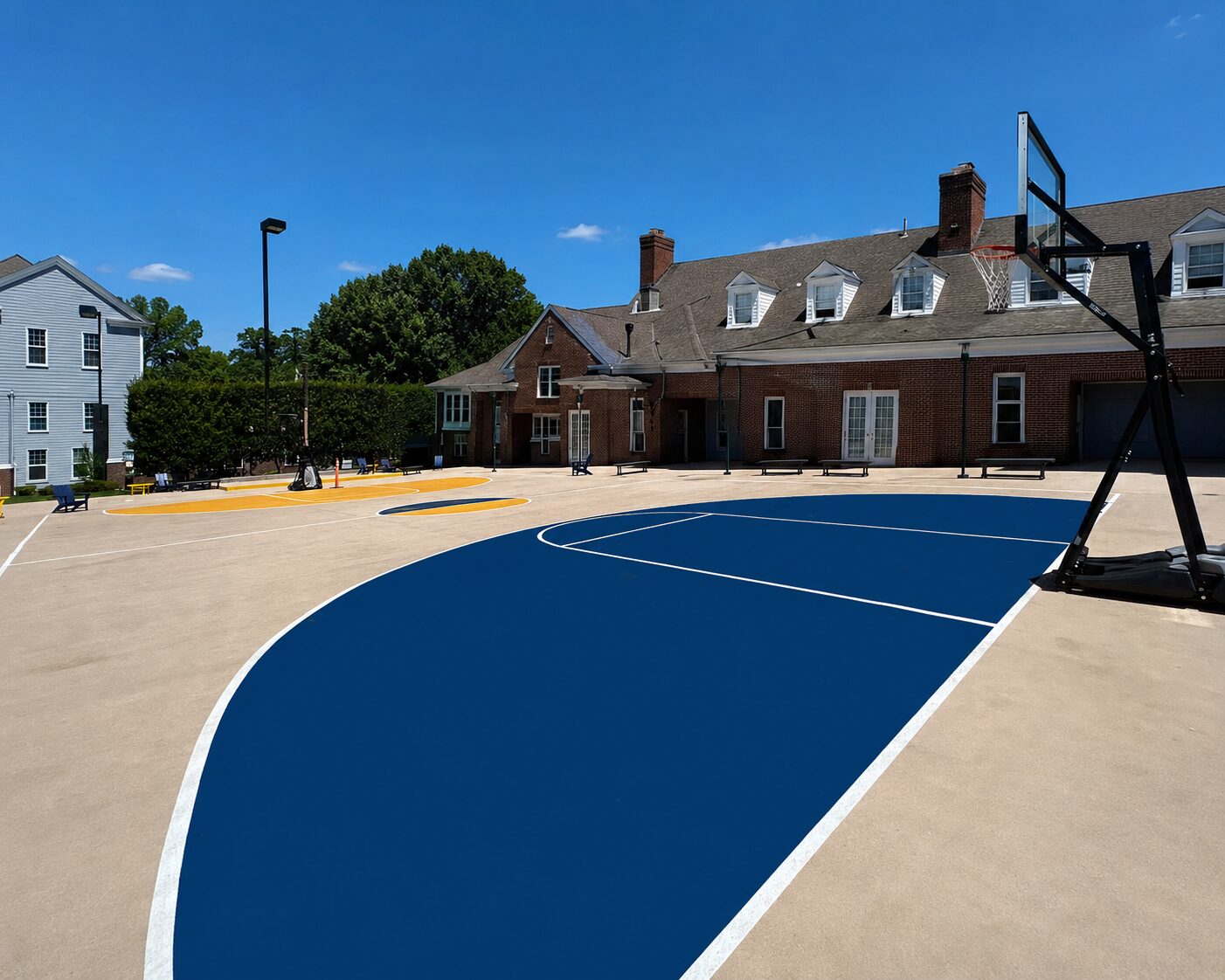 Outdoor basketball court with blue and yellow traffic coating applied to concrete surface at a commercial facility