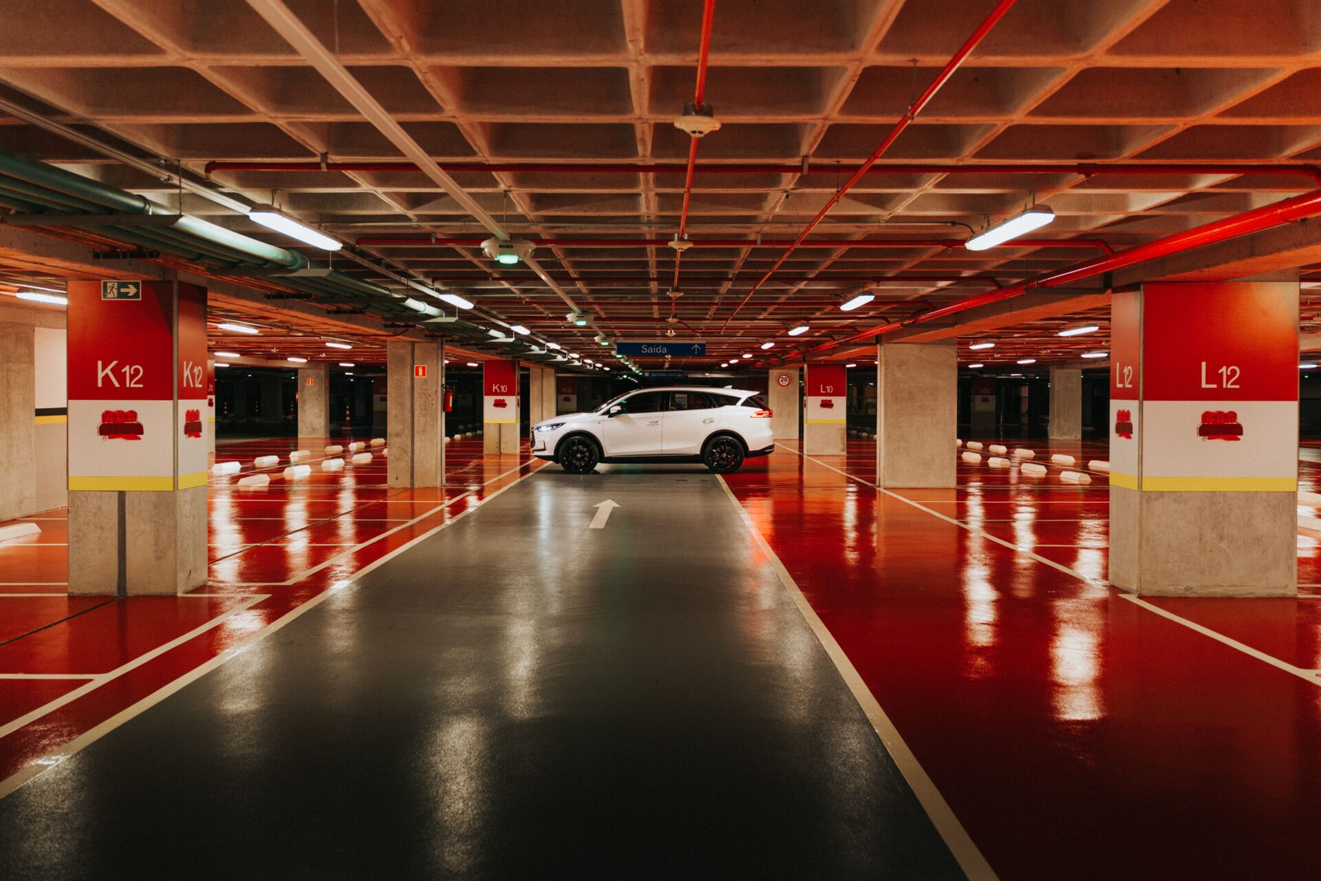 Underground commercial parking garage with professionally applied red traffic coating on parking decks clean lane striping and directional arrows