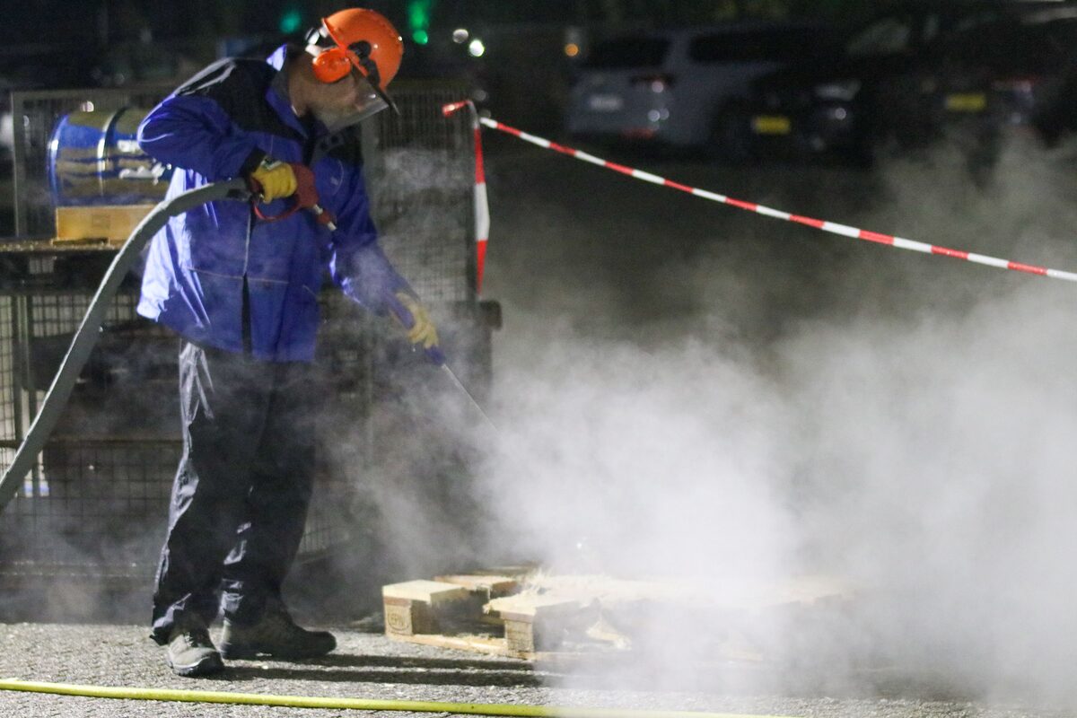 Dustless blasting contractor in protective gear using high-pressure equipment to prepare a concrete surface for commercial coating application